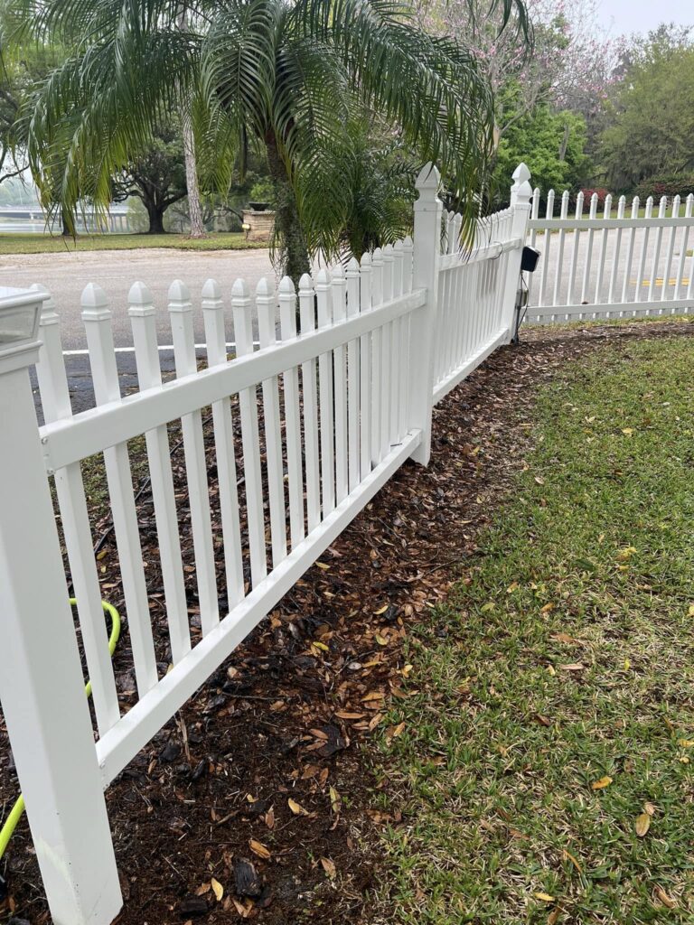 Fence Cleaning 4 a white fence next to a lawn. Professional fence cleaning in Central Florida